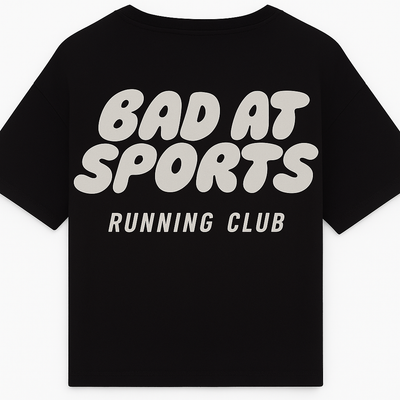Black t-shirt with 'Bad at Sports Running Club' text on a white background