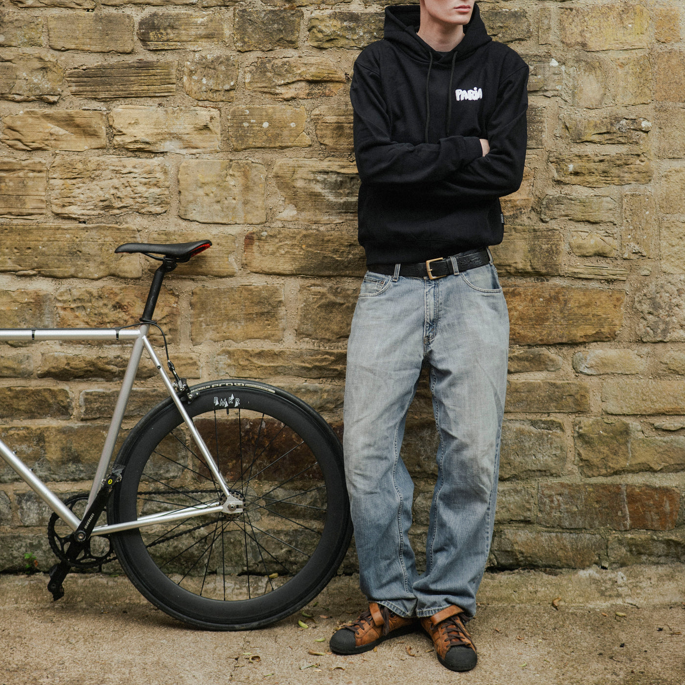 Man standing next to a bicycle against a stone wall