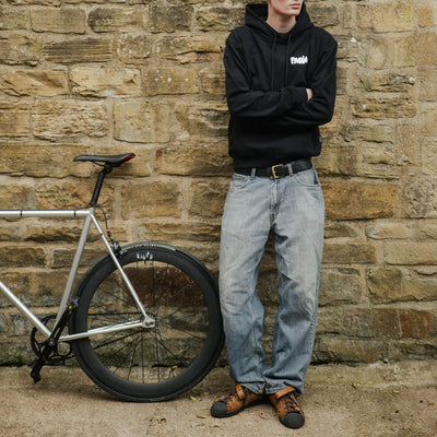 Man standing next to a bicycle against a stone wall