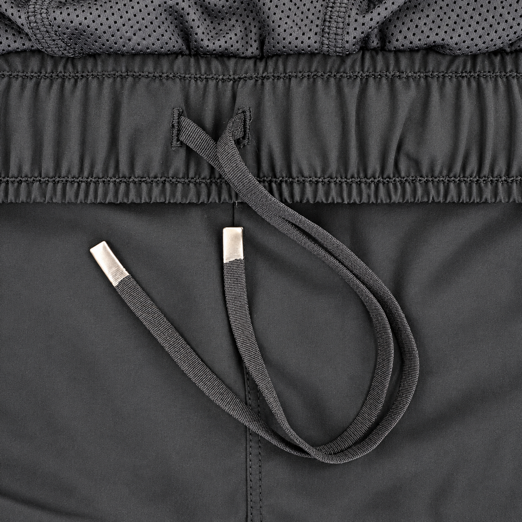 Close-up detail of a dark gray athletic garment showing the drawstring with silver metal tips, the elasticized waistband, and a perforated mesh fabric section.