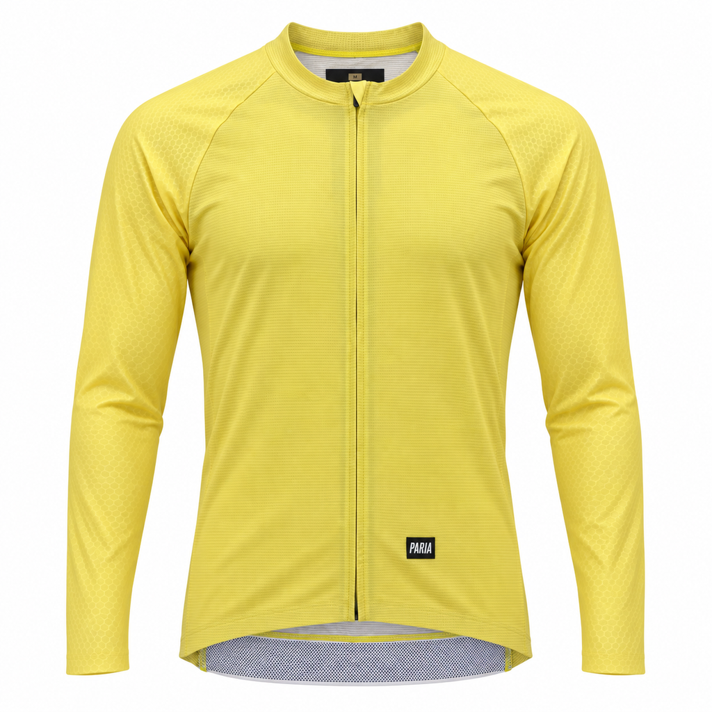 A yellow long-sleeve cycling jersey with a full-length front zipper, raglan sleeves, and a small black Paka logo patch near the bottom hem, shown on a plain white background.