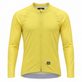 A yellow long-sleeve cycling jersey with a full-length front zipper, raglan sleeves, and a small black Paka logo patch near the bottom hem, shown on a plain white background.