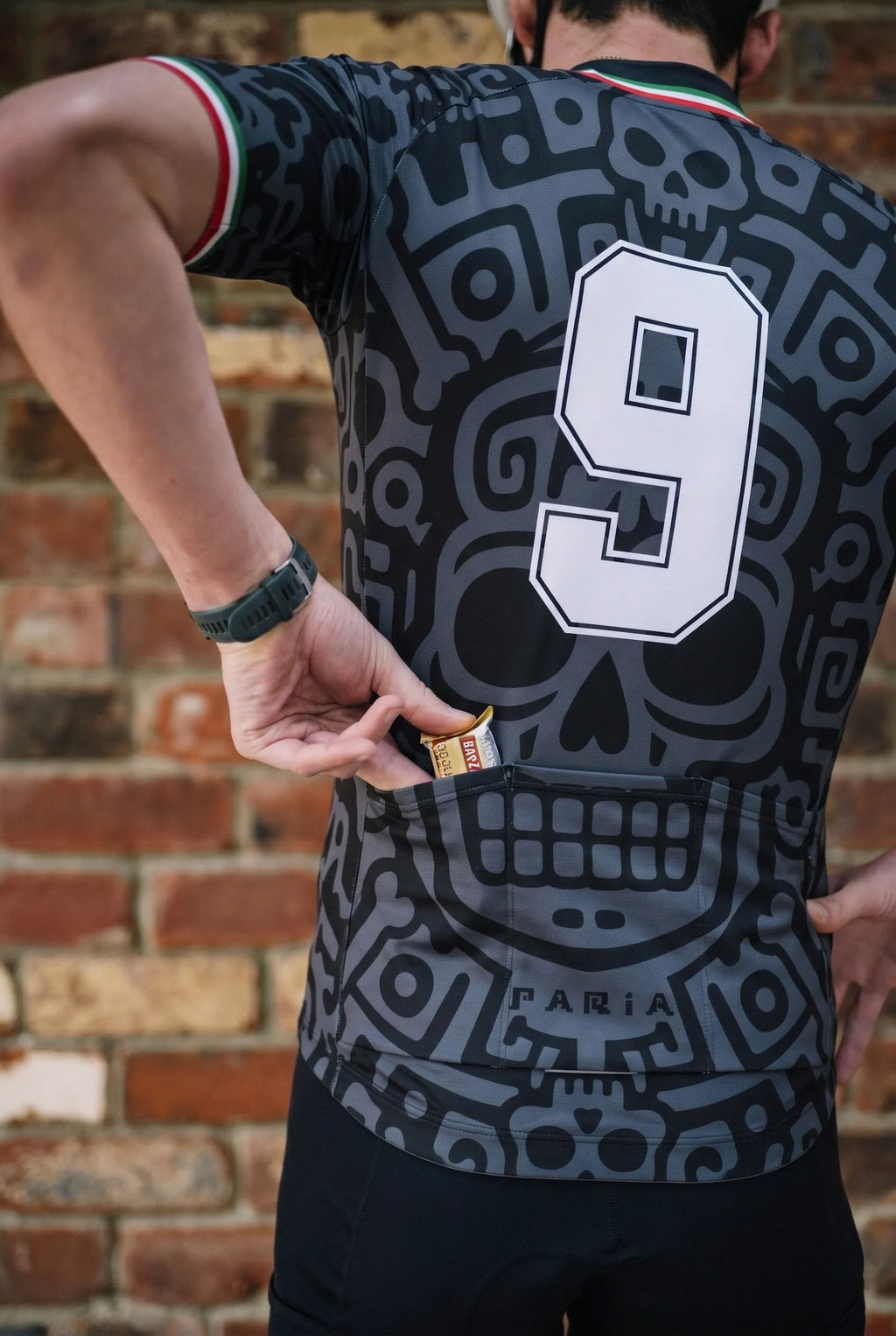 Person wearing a black sports jersey with number 9 and Faria branding against a brick wall.