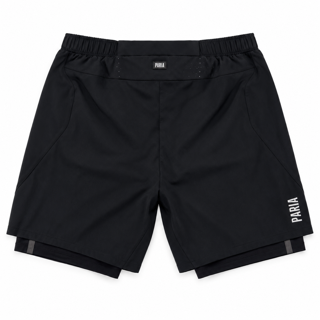Black athletic shorts with an elastic waistband, featuring a small white 'PARIA' logo on the left hip and a larger vertical logo on the right leg, shown flat on a white background.