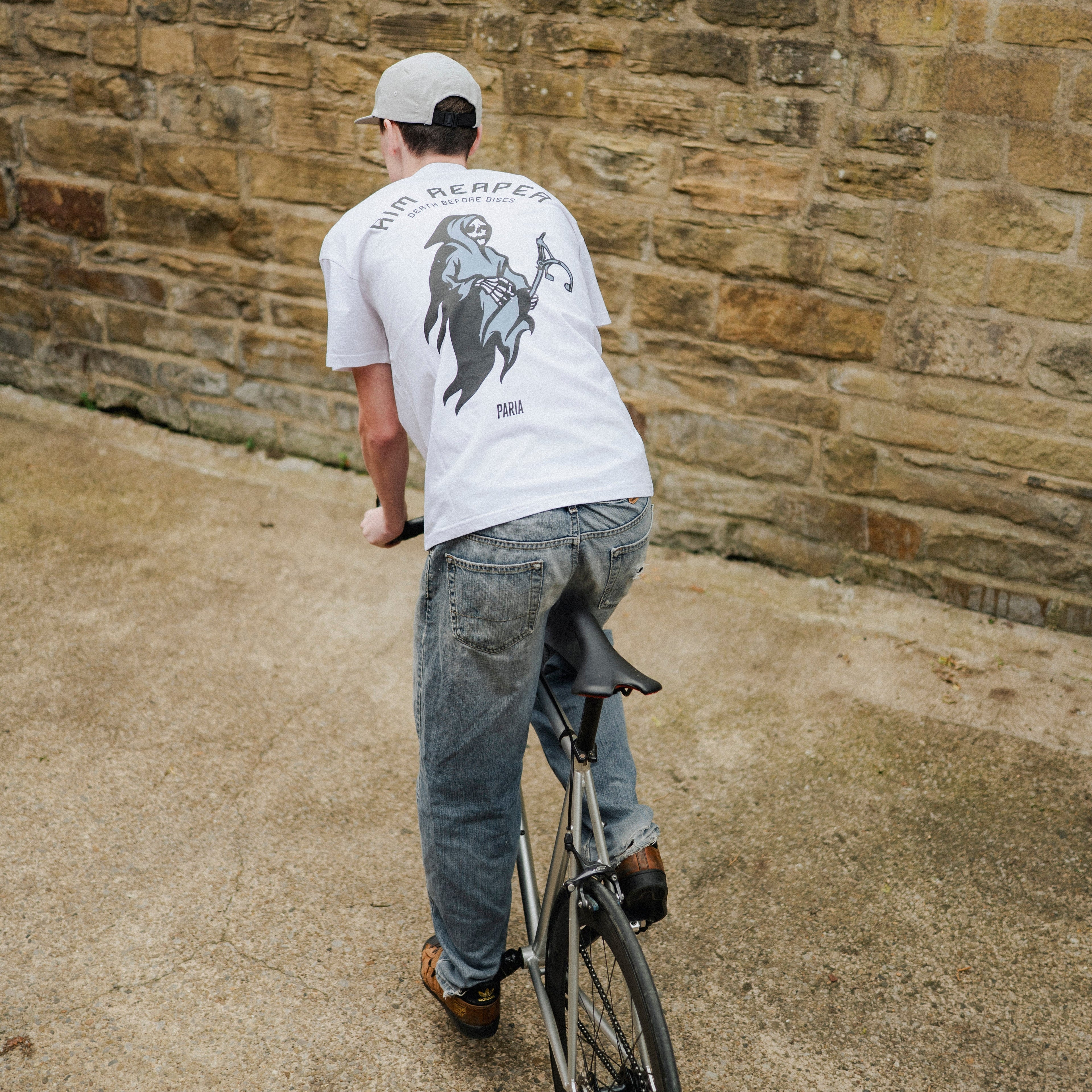 Person riding a bicycle against a stone wall.