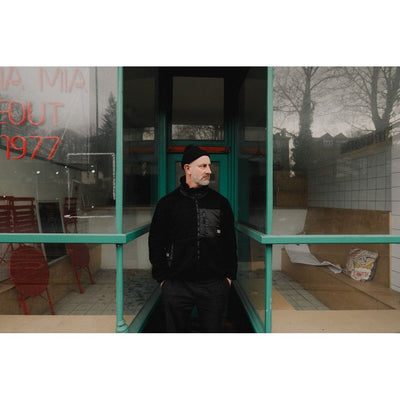 A black fleece cycling jacket with four zipped pockets and a logo on the upper left side, featuring a standing collar and zip front.