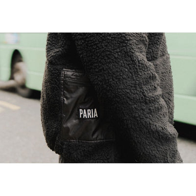 A black fleece cycling jacket with four zipped pockets and a logo on the upper left side, featuring a standing collar and zip front.