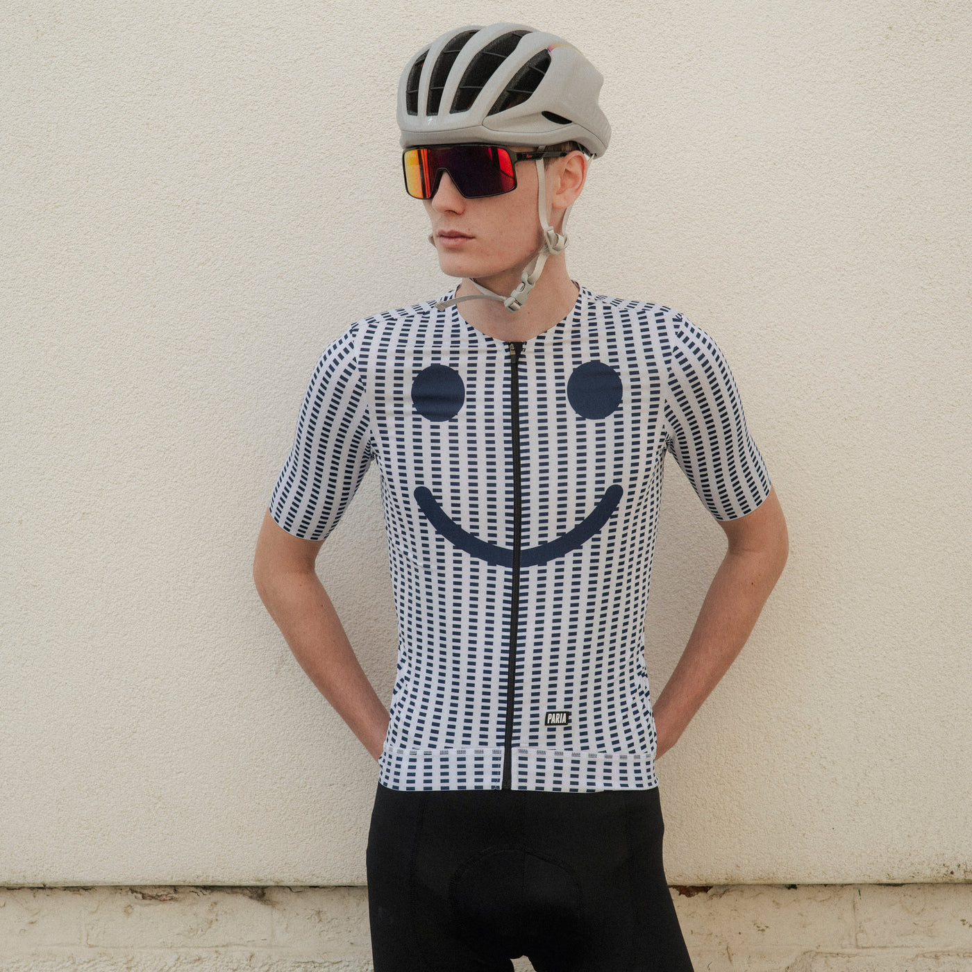 Person wearing a cycling outfit with a smiley face design on a striped background