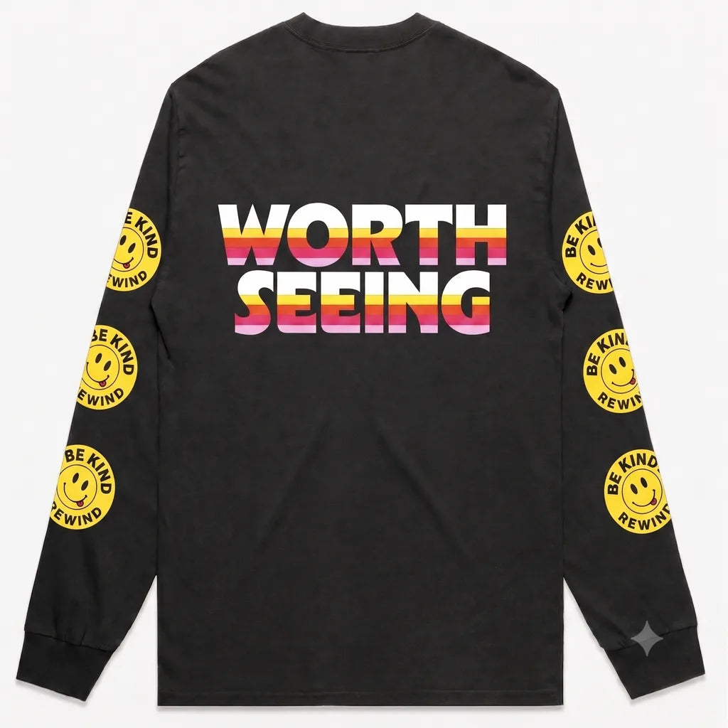 Black long-sleeve t-shirt with 'WORTH SEEING' printed on the back in a white, orange, and pink gradient. The sleeves feature yellow smiley face graphics with the text 'BE KIND REWIND'.
