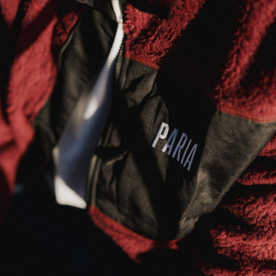 A purple fleece cycling jacket with zip pockets and contrast zips, featuring a collar and the brand name 'Paria' on the chest.