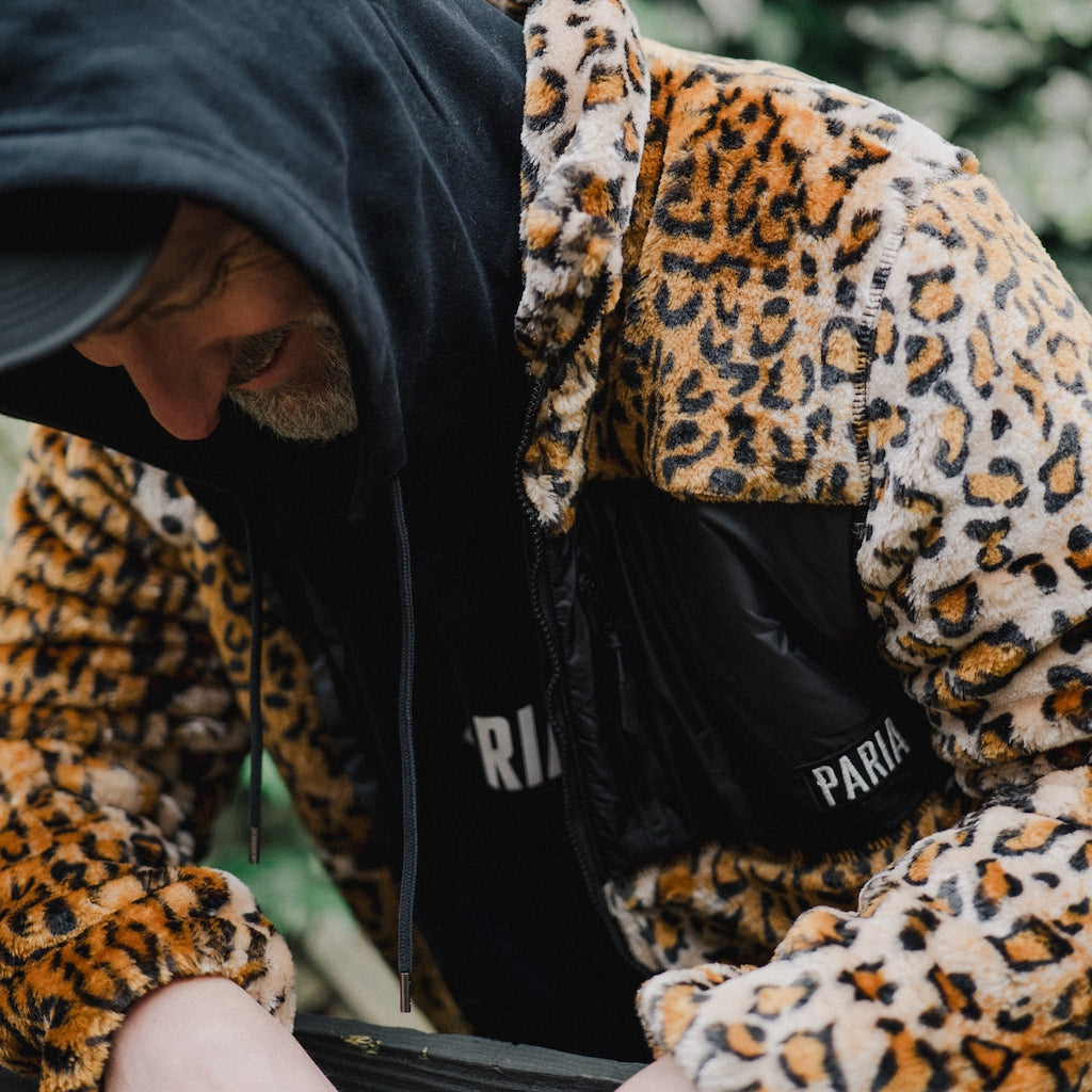 Person wearing a leopard print hoodie with a brand logo on a blurred background